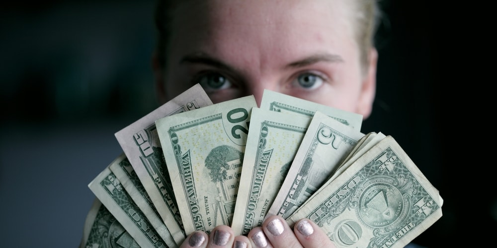 Woman covering her mouth by dollar bills