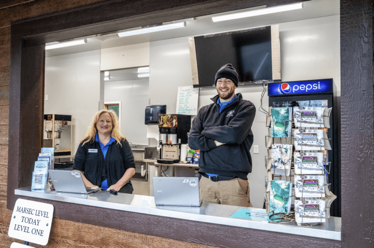 Smiling employees standing inside their stand