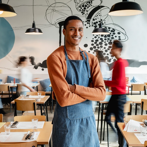 Portrait of smiling male owner or waiter in cafe with