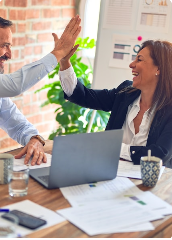 Smiling co-workers giving each other high five